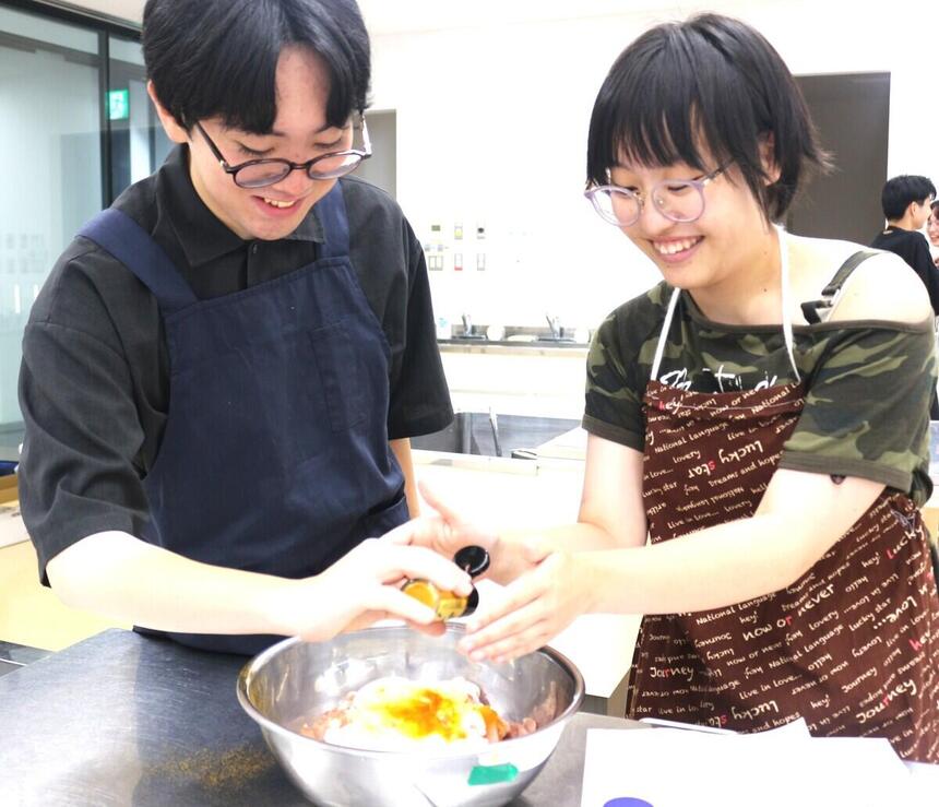 調理室で生徒同士が協力してスパイスを使い素材に下味をつけている画像