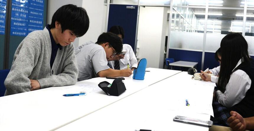 教室で生徒たちが机を囲み、スポーツイベントの企画を話し合っている様子