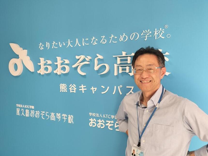 コーチが看板の前で微笑んで佇んでいる様子