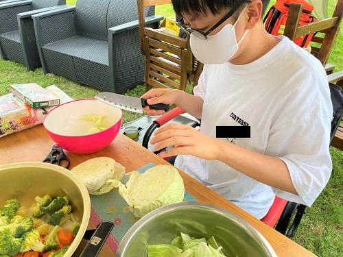 キャンプで野菜を切っている生徒