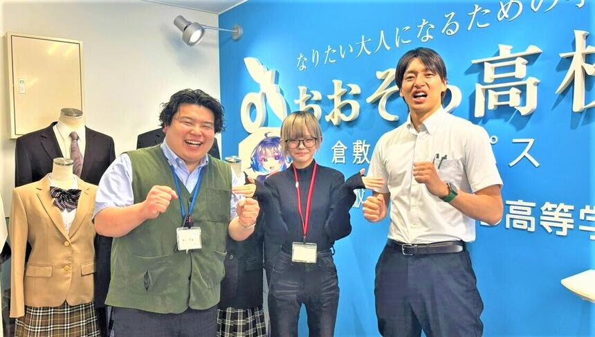 インタビューをしてくれた新入生1人とコーチ2人がキャンパス看板の前で笑顔で写っている写真