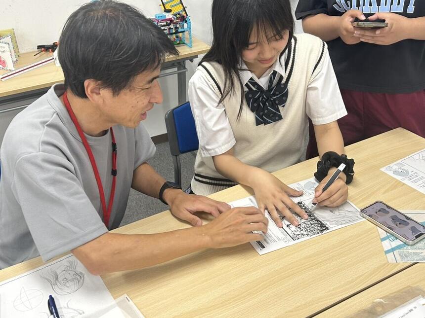 倉敷キャンパスにて、マンガイラストコースの授業中に講師から指導を受ける生徒の写真