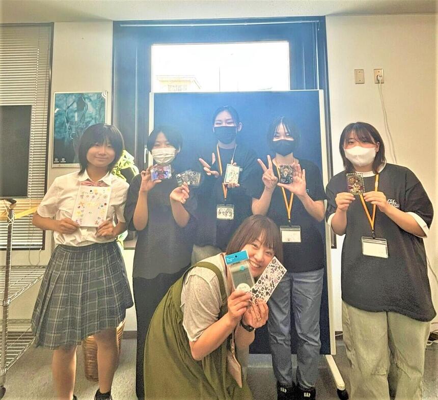 みらいの架け橋レッスン「推し活」で作ったデコレーションスリーブを持って写真に写るコーチと生徒