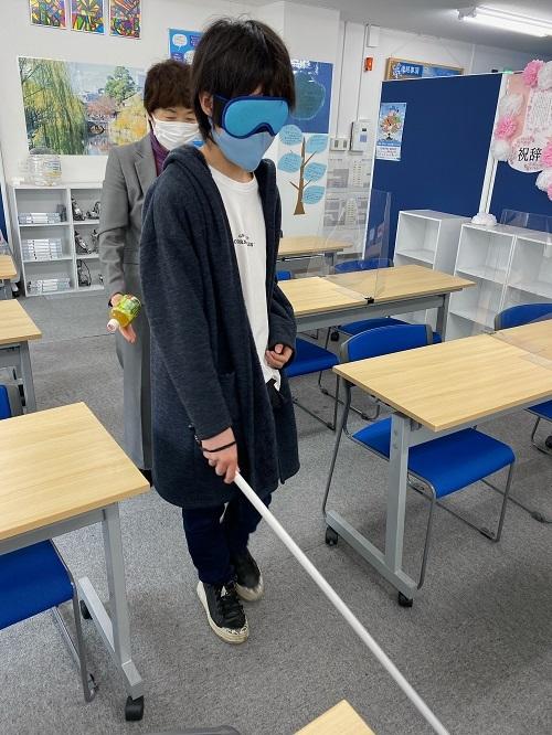 白杖を持ちアイマスクをつけて全盲の状態を体験する生徒