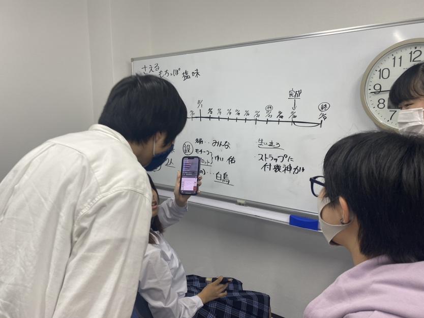 ホワイトボードに締切りまで残された時間を確認して逆算して作業工程を相談している生徒