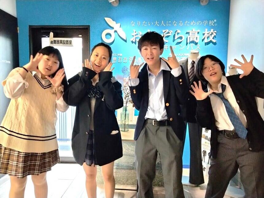 4人の生徒が笑顔で中学生を歓迎している写真