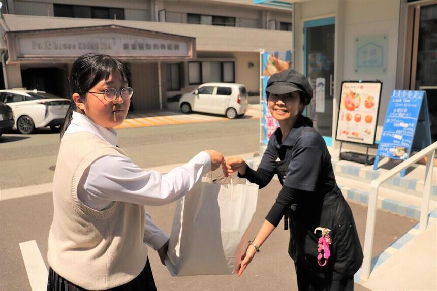 生徒がエサ皿を受け渡しているシーン