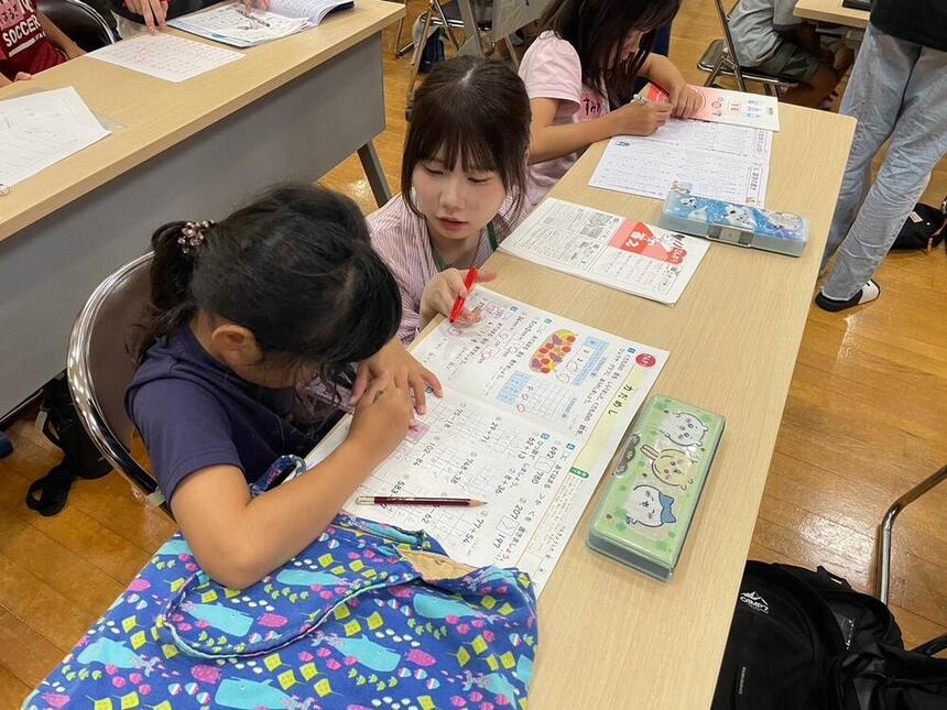 夏休みの宿題を地域の小学生に教えている高校生ボランティア