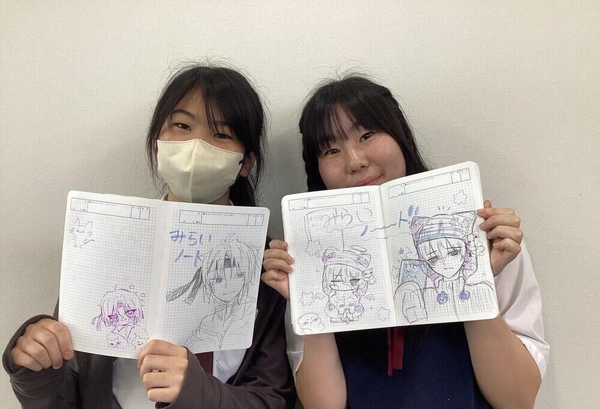 2人の女子生徒が自分で描いたみらいノートを笑顔で持っている写真。