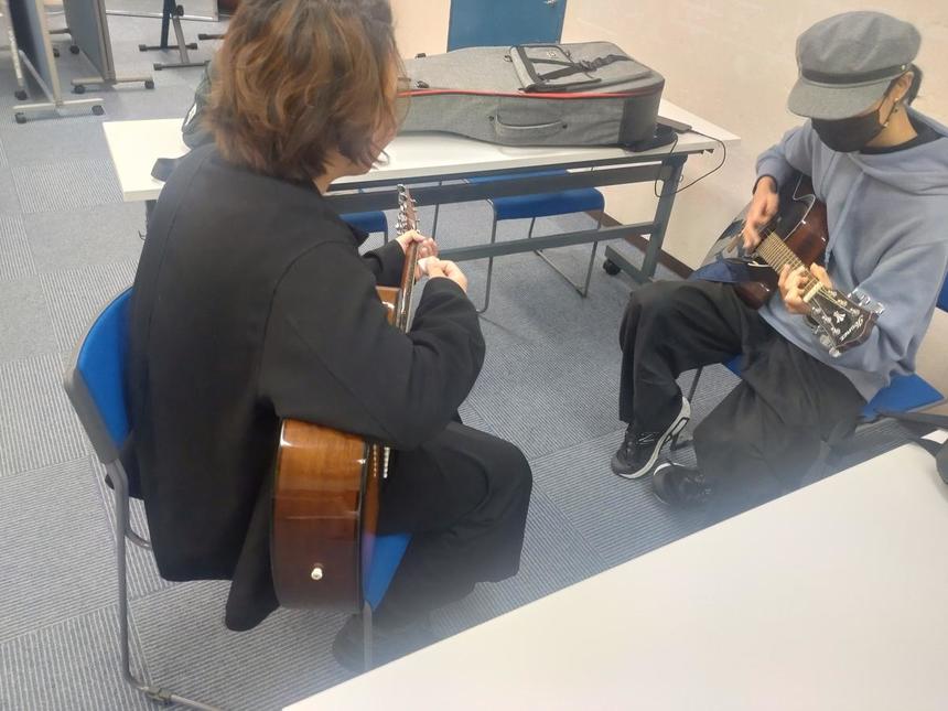 みらいの架け橋レッスン®ミュージックの時間。生徒二人でギターを教えあいっこしている写真。