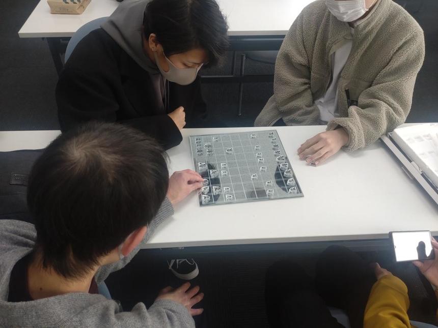将棋をしている生徒と、それを見学している生徒たち