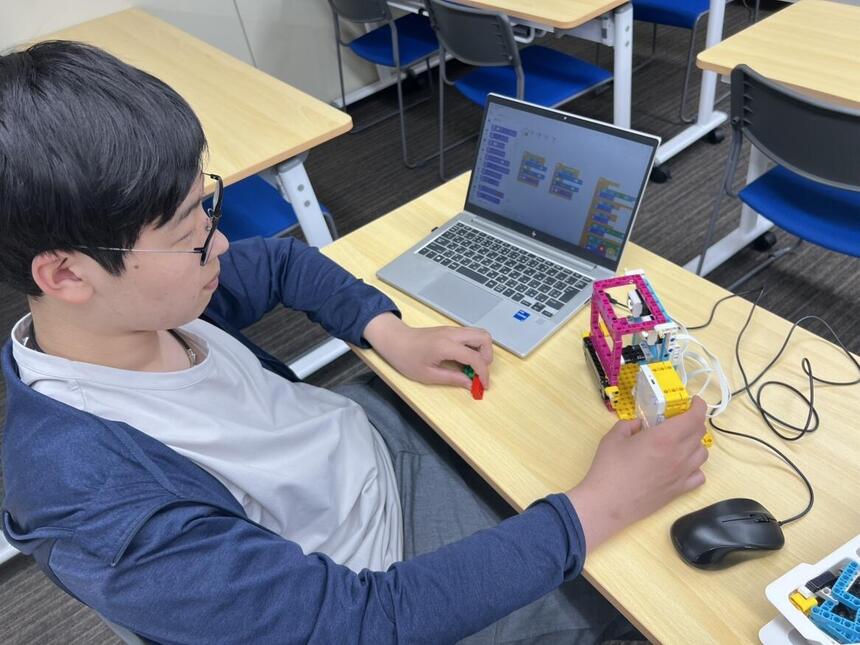 プログラミングコースで自動販売機のプログラムを熱心に改良しているインタビュー生徒