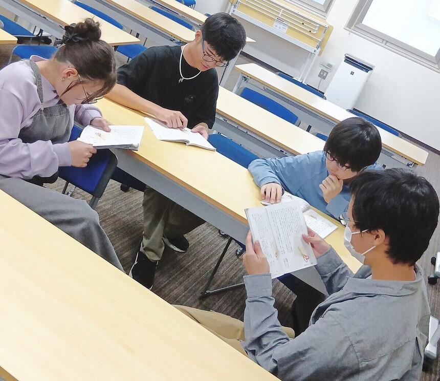 おおぞら高校京都キャンパスの生徒４名が教科書を手に取り話し合いをしている画像。