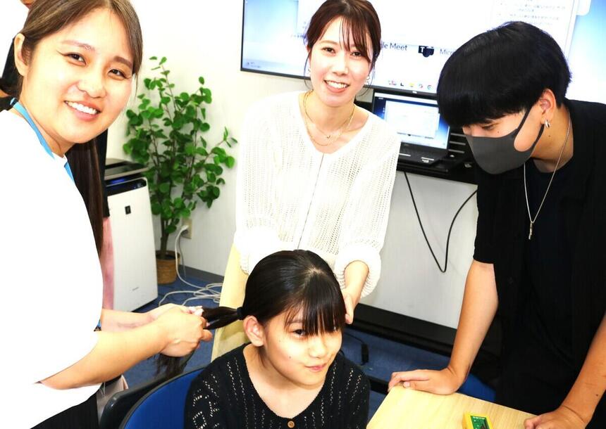 2年生の女子生徒がみらいの架け橋レッスン®の授業内で、お互いのヘアメイクやおでかけコーデを紹介し合って笑顔で楽しんでいる写真。