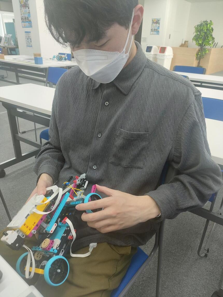 Yさんがロボットの車輪を手で調整している姿