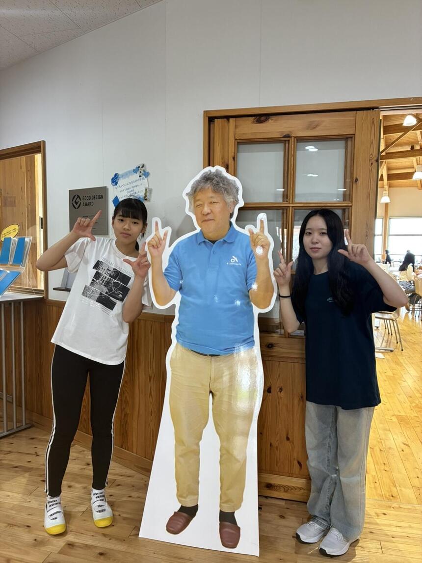 食堂前で屋久島おおぞら高等学校の茂木健一郎校長のパネルと写真撮影する生徒