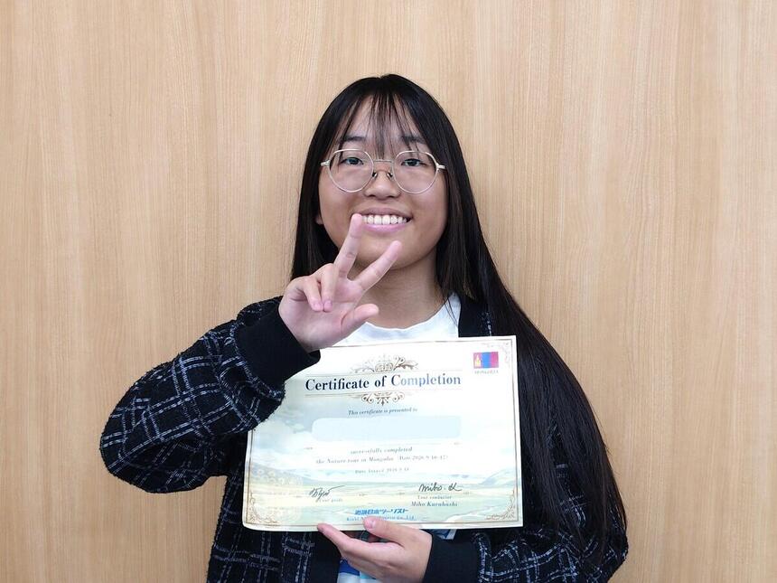 留学後、町田キャンパスにて、ネイチャーツアーinモンゴルの修了証を持って写真に写る生徒