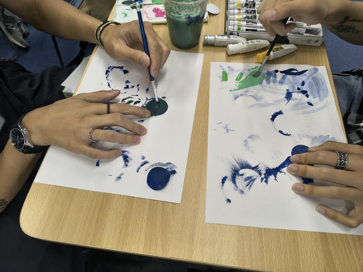生徒が色を塗り重ね、丸い紙の上に宇宙を描く様子