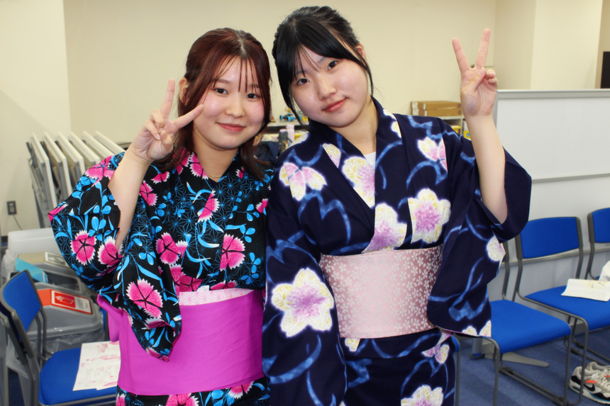 浴衣を着た2人の女子生徒が笑顔でピースサインをしている写真。