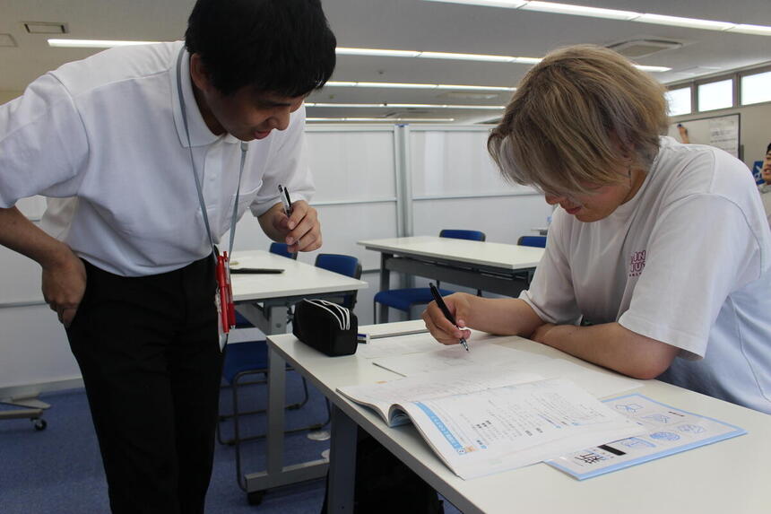 数学を教えるコーチと真剣に学習に取り組む生徒