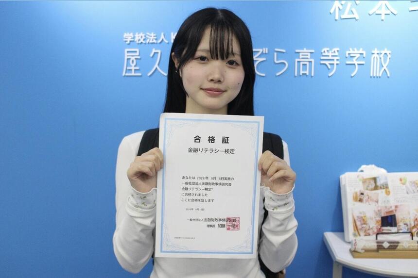 金融リテラシー検定に合格し、合格証とともに記念写真を撮影する生徒