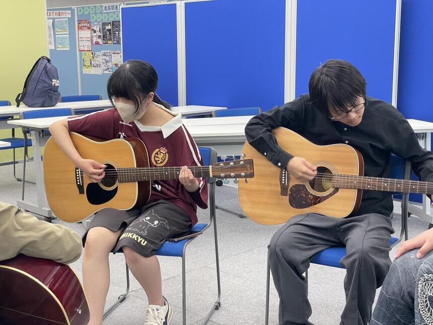 ギターを弾く男子生徒と女子生徒