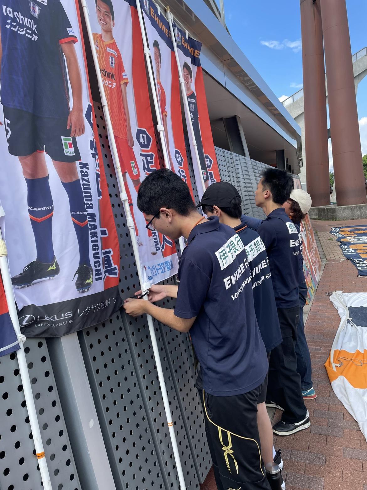 愛媛FCのスポンサーの幕を協力して設置している生徒