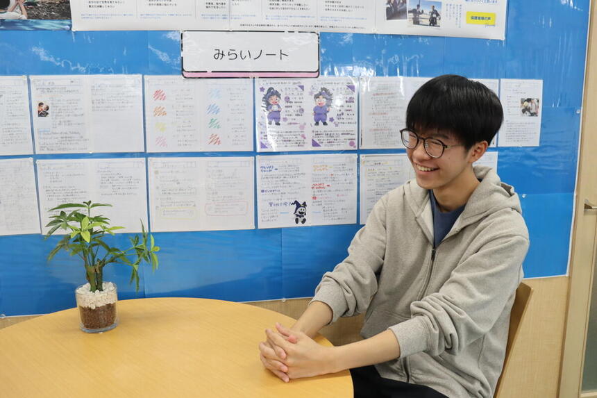休み時間に生徒が椅子に座ってインタビューを受けている様子