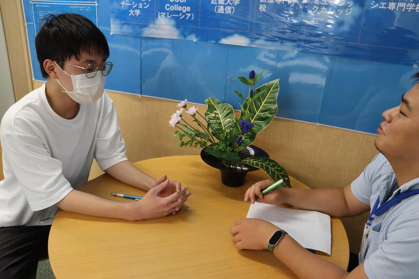 キャンパスでコーチと楽しく面談をしている新入生の様子
