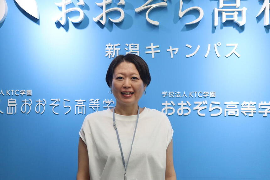 新潟キャンパス正面入口前で、新しく着任したコーチが笑顔で自己紹介をしている写真