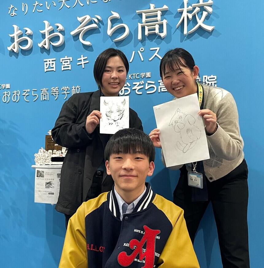 体験授業を担当する講師がイラストを手に持って、在校生が顔を出していくれている様子