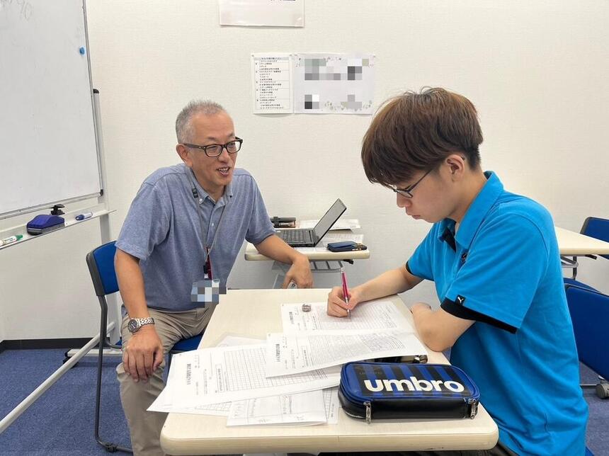 コーチが生徒に受験対策で勉強を教えている様子