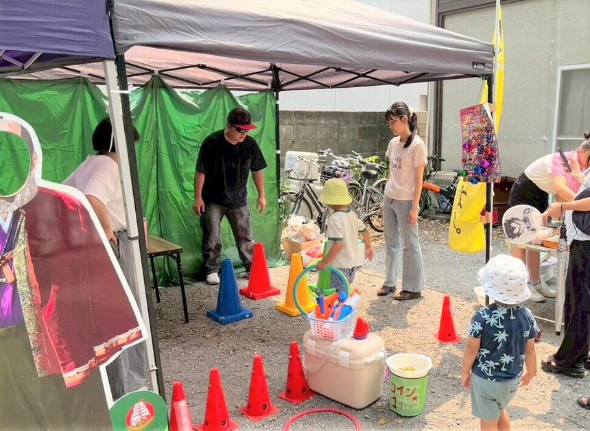 「天神さま夢通り」の縁日ブースでお手伝いをしている生徒と楽しんでいる子どもたち
