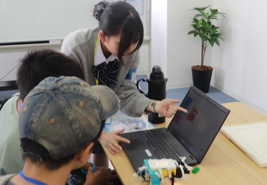 オープンキャンパスで岡山キャンパスの教室内で中学生に向けてアドバイスをする在校生の写真