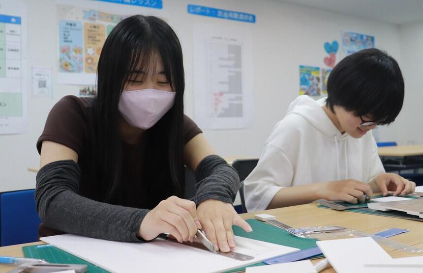 岡山キャンパスの住環境デザインコースに所属する生徒が教室内でスチレンボードを使い模型製作に取り組む様子。