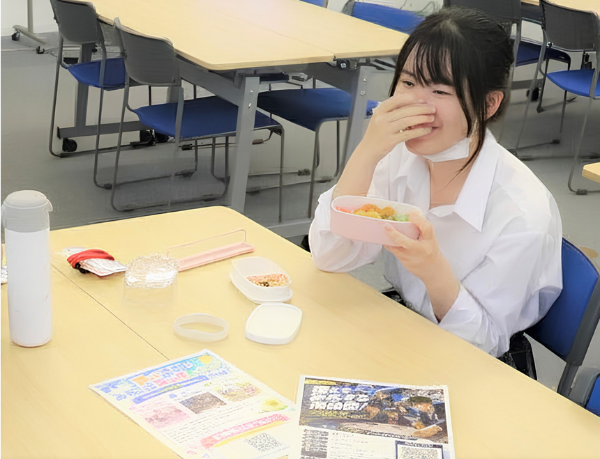 岡山キャンパスの教室で、入学前からオープンキャンパスや体験授業に参加していた1年生のAさんが、笑顔で友人たちと談笑している様子。