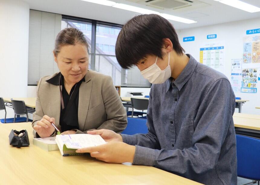 教室内でコーチが生徒に勉強を教えている写真