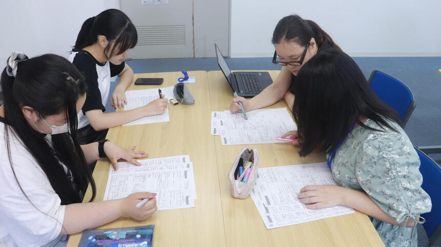 教室内でコーチと生徒が進路指導で求人を見ている写真