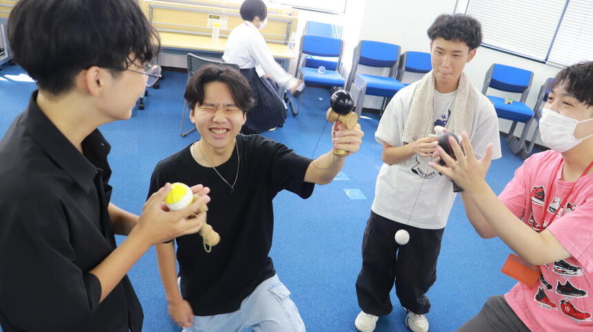 Fくんが教室で大道芸のみらかけ時間にけん玉で成功したところを周りの生徒に見せている様子