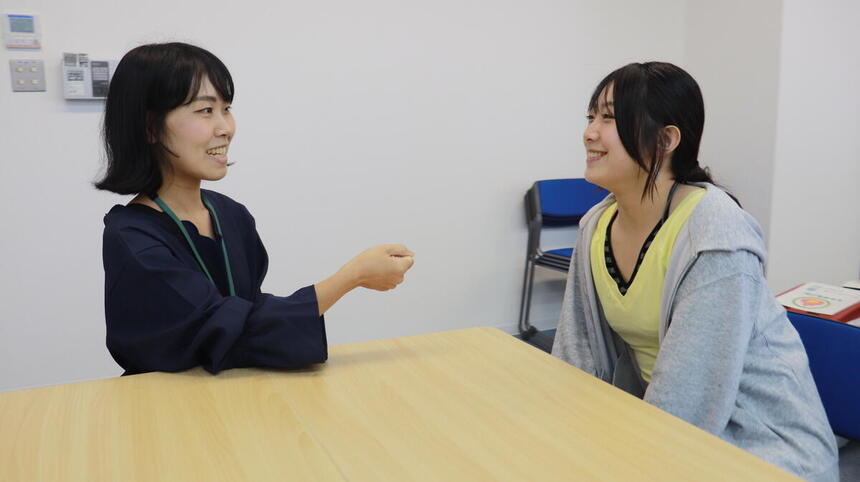教室内でコーチが生徒にインタビューをしている写真