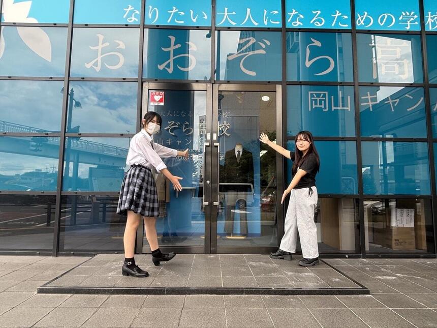 お昼過ぎにおおぞら高校岡山キャンパスの入り口前で高校生2名が両手を広げている写真