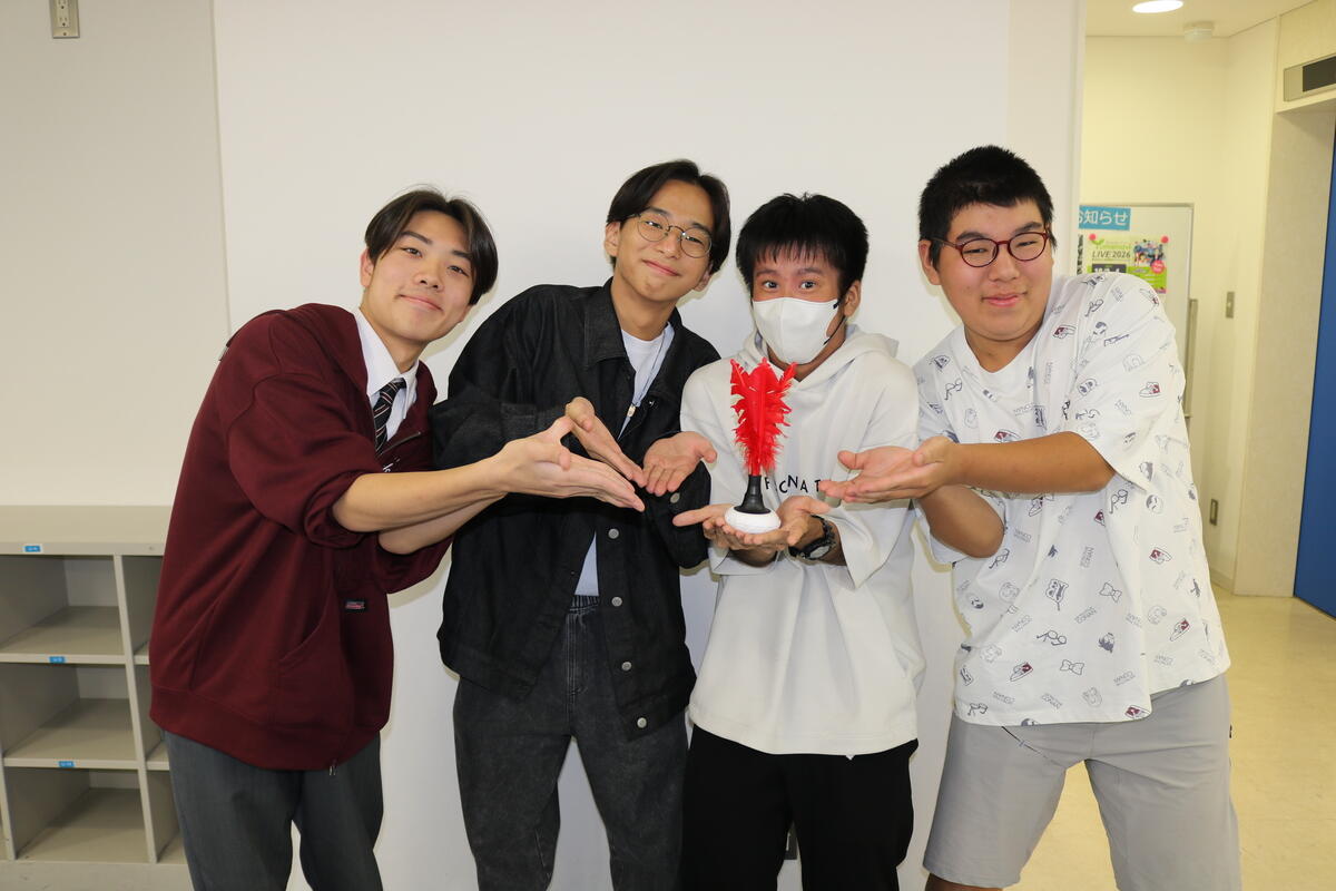 室内で生徒がインディアカの羽を撮影者に見せている様子