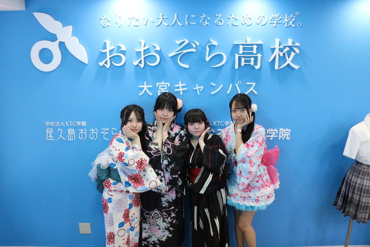 浴衣を着た生徒4人が、大宮キャンパスのボードの前で記念撮影している様子