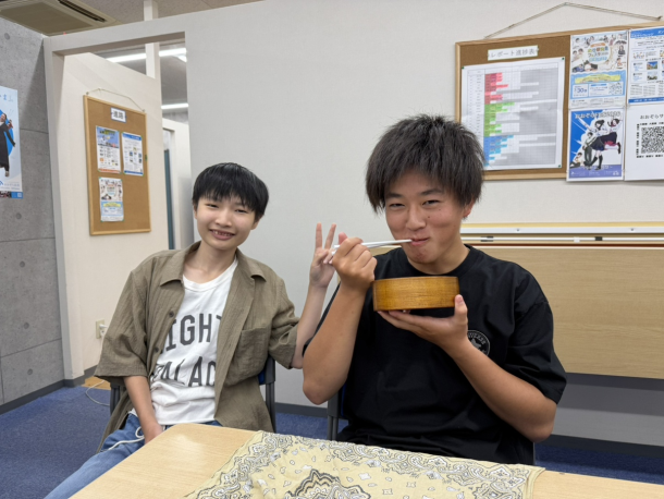 お昼休みにお弁当を食べながら、近くにいた生徒に見守られつつインタビューに答えてくれた生徒の様子