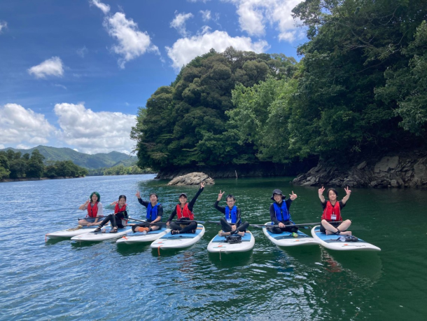 夏のみえ大台センバスキャンプで大自然の中、参加者の生徒とSUPを楽しんでいる様子。