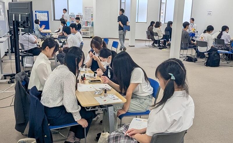 ブースで話を聞く、生徒と担当者