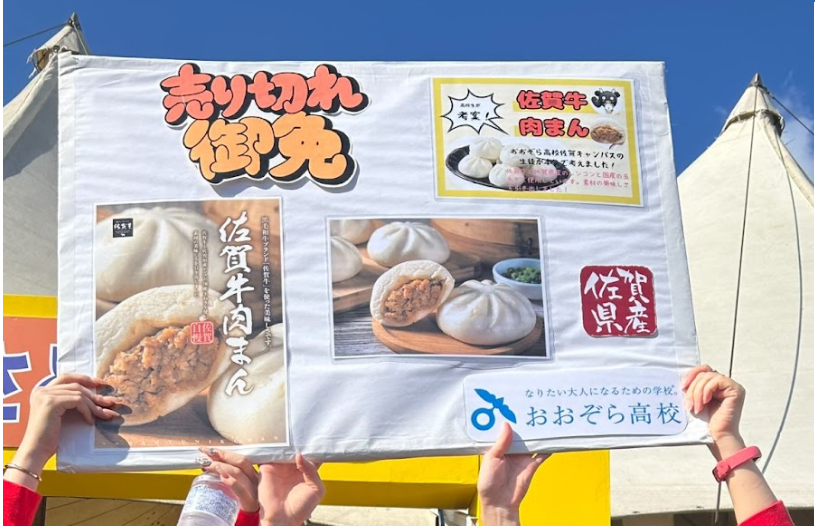 佐賀牛肉まんの看板を掲げる生徒とコーチ