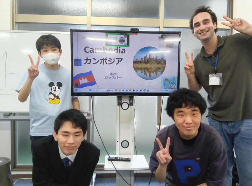 佐賀キャンパスの教室でスライドショー前で写真撮影をする参加生徒と外国人ボランティア