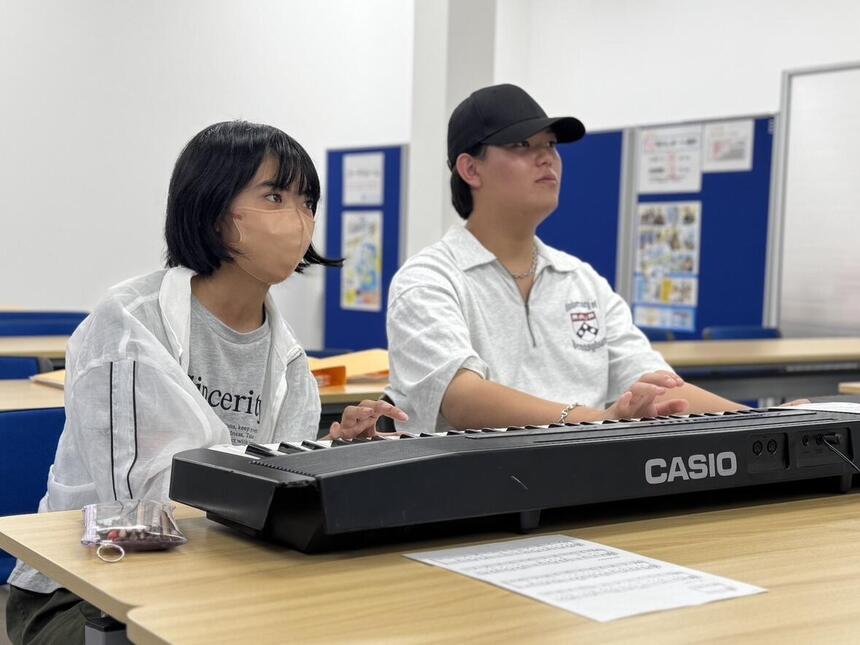 教室で横に並んでピアノに向かっている男子生徒と女子生徒