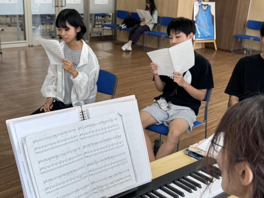佐賀キャンパス内のホールで楽譜を見ながら歌う、女子生徒と男子生徒